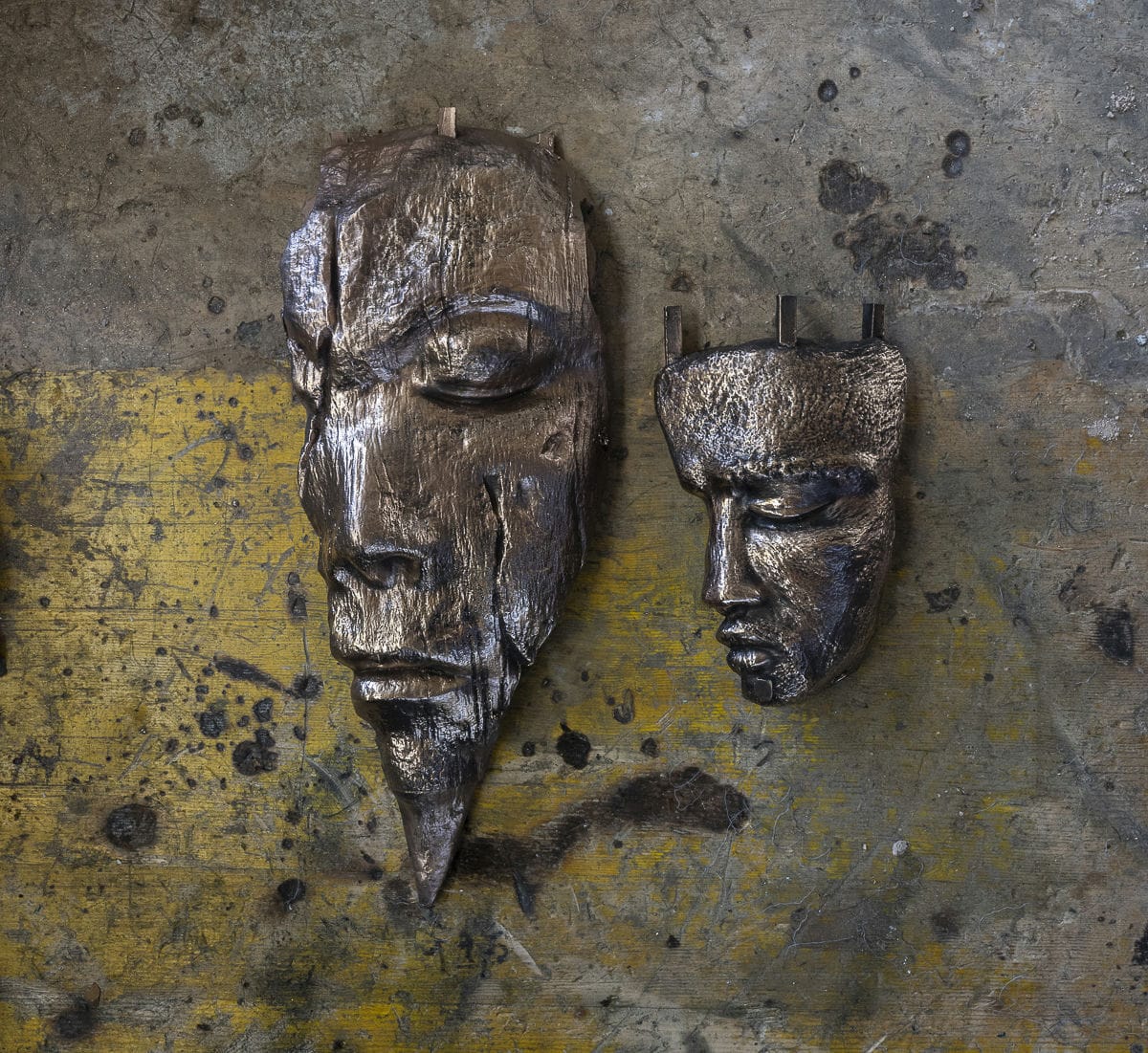 Two bronze-cast faces on the workbench of the De Carli foundry in Volvera