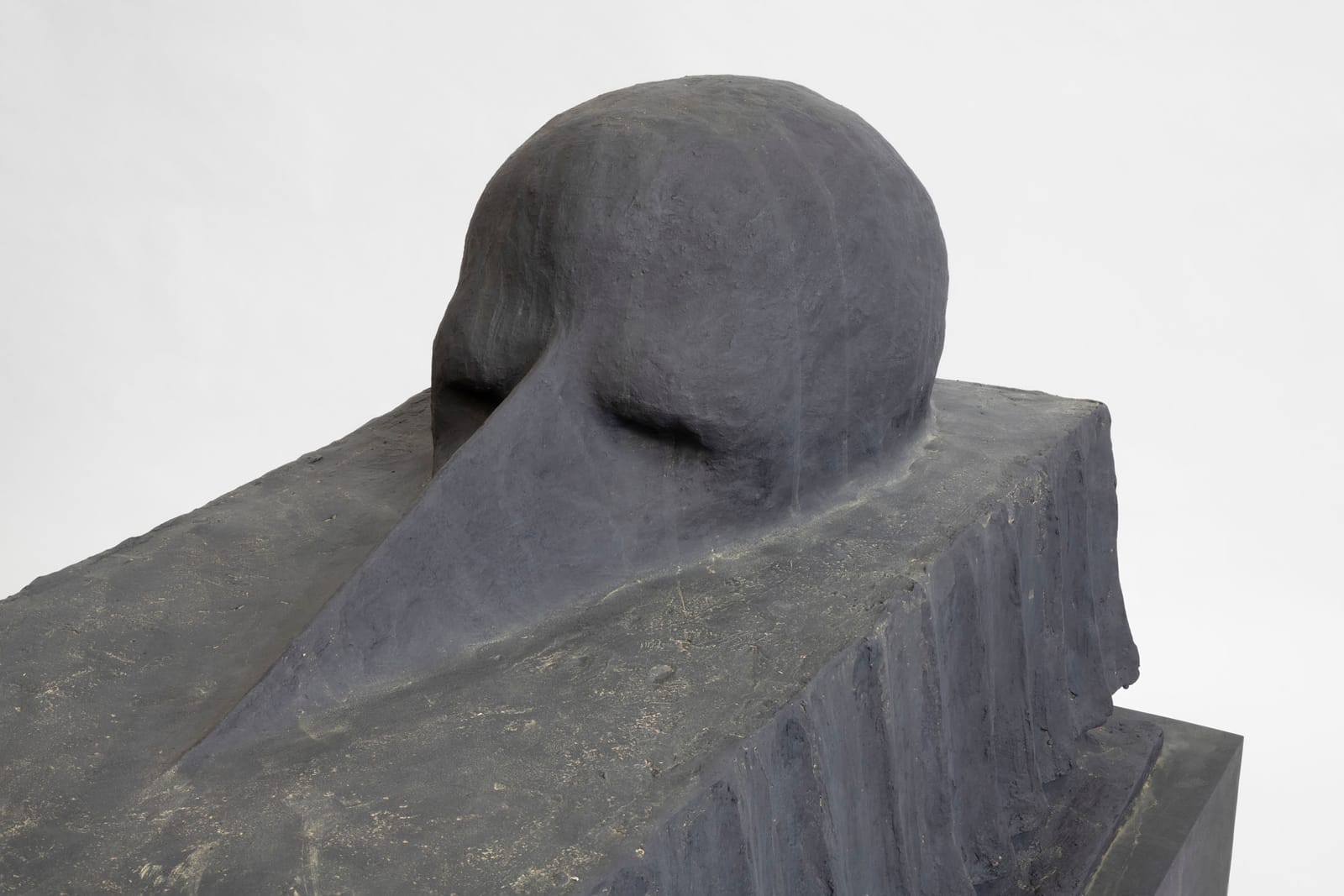 Long-beaked head resting on a dark block, patinated bronze sculpture, close-up