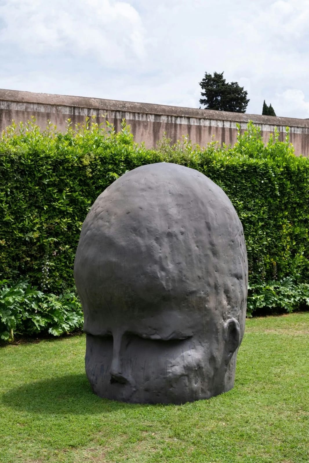The monumental head seen close up against a clipped hedge in the Villa gardens