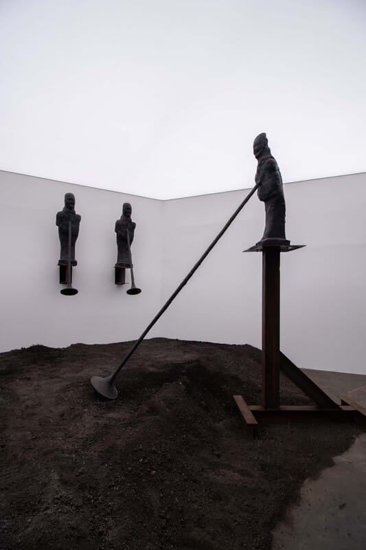 Mound of dark earth at the foot of the bronze figures, corner of the white room